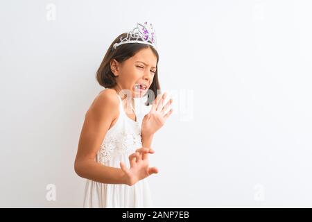 Bella ragazza bambino indossando princess crown in piedi isolato su sfondo bianco disgustato espressione, orinato e timorosi facendo il disgusto di fronte essere Foto Stock