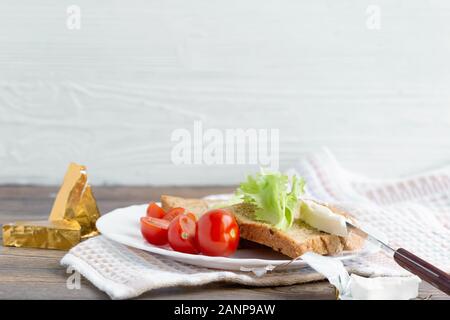 Panini con formaggio morbido, lattuga e pomodori sul pane di grano. Foto Stock