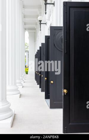 Ingresso con porte nere aperte all'edificio del College of Medicine a Singapore Foto Stock