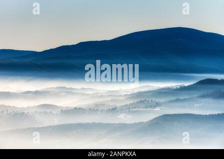 Sagome di mattina inverno le montagne nella nebbia Foto Stock