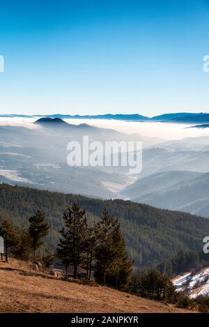 Sagome di mattina inverno le montagne nella nebbia Foto Stock