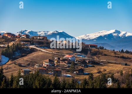 Villaggio bulgaro Smolevo in montagne Rodopi nella parte anteriore del Rila innevate vette Foto Stock