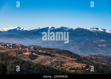 Villaggio bulgaro Smolevo in montagne Rodopi nella parte anteriore del Rila innevate vette Foto Stock