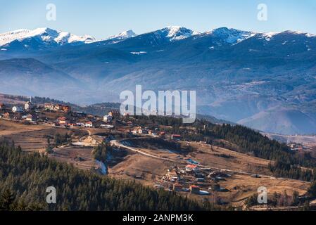 Villaggio bulgaro Smolevo in montagne Rodopi nella parte anteriore del Rila innevate vette Foto Stock