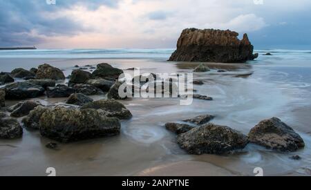 Rocce di onde e il tramonto sulla spiaggia Foto Stock