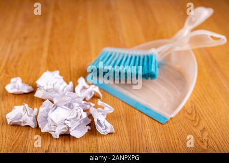 Paletta di plastica e pennello su un pavimento di legno. Spazzare i rifiuti a casa. Sfondo scuro. Foto Stock