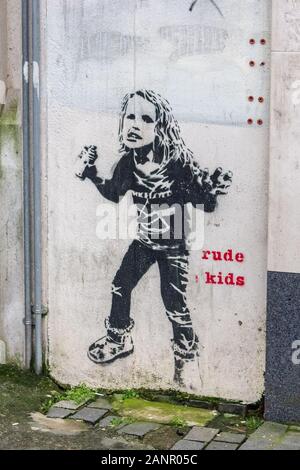 Ragazza giovane con la bomboletta spray wall art graffiti murali e rude kids caption per artista Dotmaster, Williamson Square, Liverpool Foto Stock