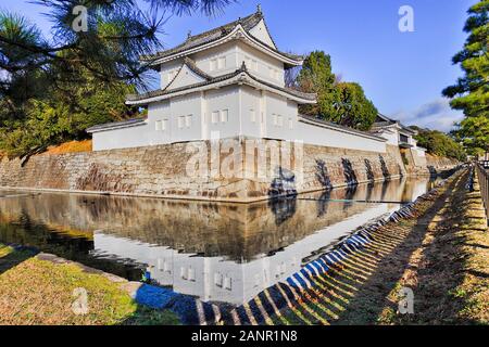 Angolo bianco torre di avvistamento di Kyoto il castello Nijo - Palazzo del shogunato giapponese. Morbida luce mattutina che riflette ancora in acque di fossato circostante. Foto Stock