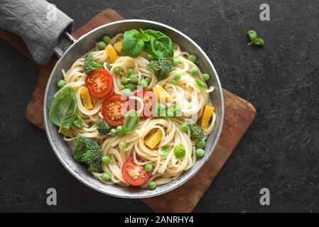 Pasta Spaghetti Primavera, vegetariane piatto di pasta con verdure pomodoro, broccoli, verde pisello, peperone e le foglie di basilico, vista dall'alto, copia dello spazio. Foto Stock