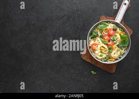 Pasta Spaghetti Primavera, vegetariane piatto di pasta con verdure pomodoro, broccoli, verde pisello, peperone e le foglie di basilico, vista dall'alto, copia dello spazio. Foto Stock