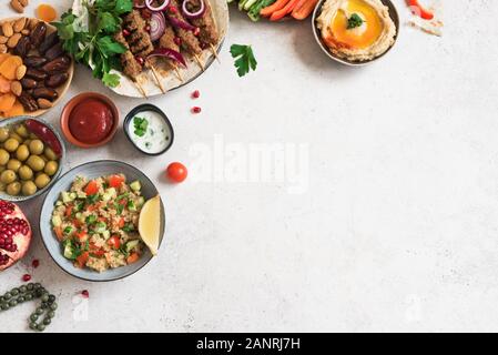 Arabo e ristoranti mediorientali, tavolo per la cena. Spiedini di carne, hummus, tabulé insalata, delle salse tradizionali, olive, pita, date di frutta, melograno. Foto Stock