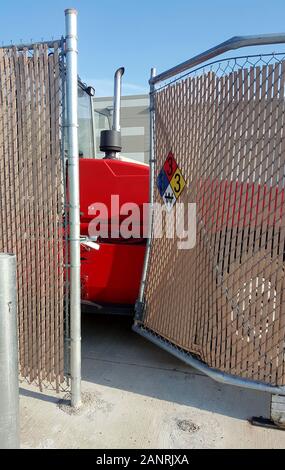 Danni al cantiere di un cancello che conduce ad un magazzino. Un rosso non identificato veicolo industriale sta bloccando il punto di ingresso. Foto Stock