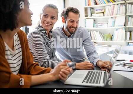 Lavorando insieme sul progetto. Felice giovani colleghi di lavoro lavoro in ufficio Foto Stock