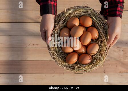 Le donne portano a strisce rosse camicie, mettere le uova fresche in rattan cestelli disposti sul pavimento in legno. Foto Stock