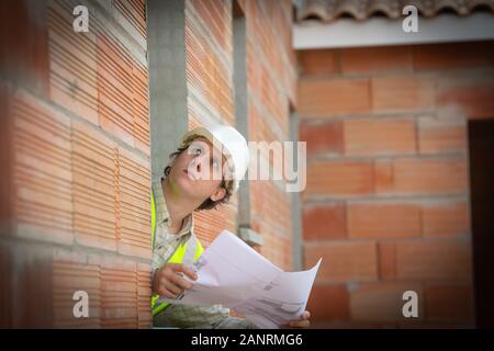 Ingegnere professionale architetto lavoratore con casco protettivo e blueprint di carta a casa costruzione edilizia di sfondo del sito Foto Stock