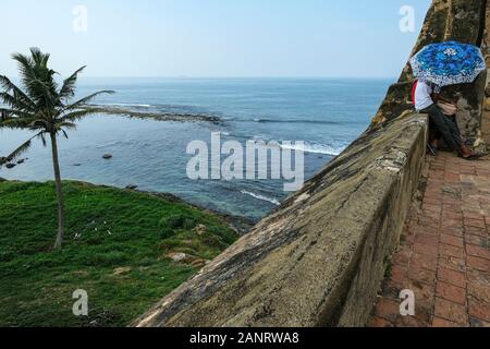 Galle, Sri Lanka - Gennaio 2020: Una giovane coppia è coperta da un ombrello sulle pareti del Forte di Galle il 14 gennaio 2020 a Galle, Sri Lanka. Foto Stock