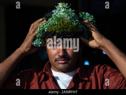 Ritratto di un fiore uomo regolazione di una corona di fiori sulla testa, Jizan provincia, Sabya, Arabia Saudita Foto Stock