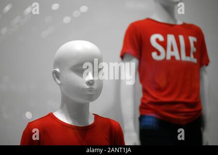 Due bambini di bianco manichini in T-shirt rosse con la scritta vendita su sfondo grigio. Close up. Foto Stock