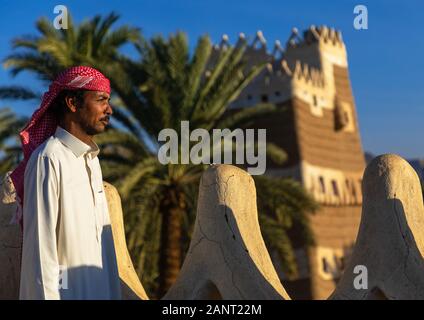 Arabia uomo in piedi sulla terrazza merlata della sua casa di fango, Najran provincia Najran, Arabia Saudita Foto Stock