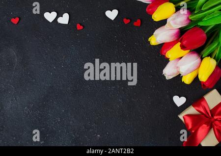 Bouquet di tulipani e confezione regalo su sfondo scuro. Molla dello sfondo. Biglietto di auguri per il giorno di San Valentino, Festa della donna e la Festa della mamma. Vista superiore, copia Foto Stock