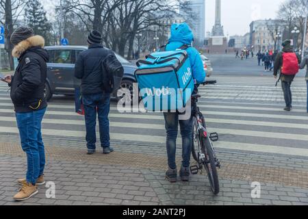 Città di Riga, Lettonia. Consegna rapida di cibo in bicicletta. Un ciclista sorge sulla strada con una scatola di cibo. 18.01.2020 Foto Stock