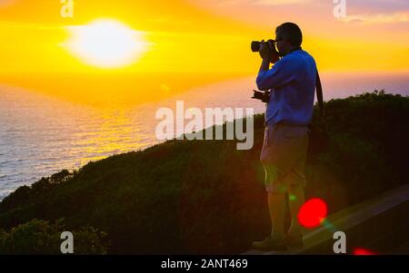 Uomo di scattare le foto del tramonto a Portoscuso CARBONIA Sardegna reflex Foto Stock