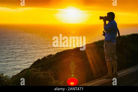 L'uomo prende le foto del tramonto a Portoscuso CARBONIA Sardegna reflex Foto Stock