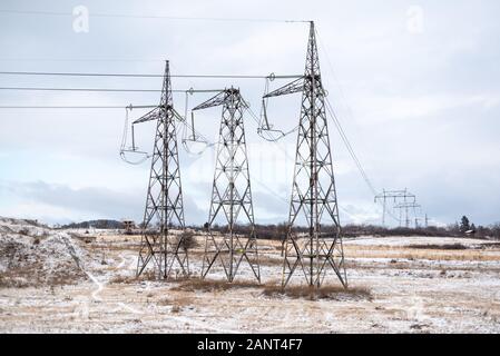 supporto elettrico ad alta tensione. Cielo nuvoloso 3 pilastri simmetria lunga distanza in inverno freddo bianco nevoso. L'industria energetica. La corrente passa attraverso Foto Stock