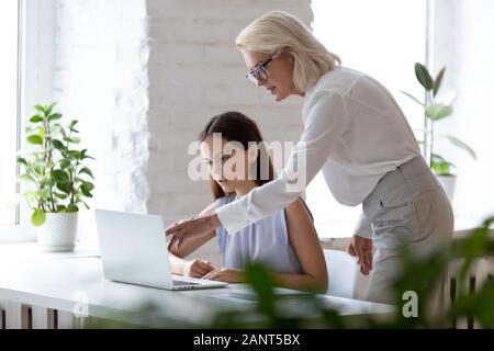 Di mezza età boss femmina spiegando applicazione aziendale al nuovo dipendente Foto Stock