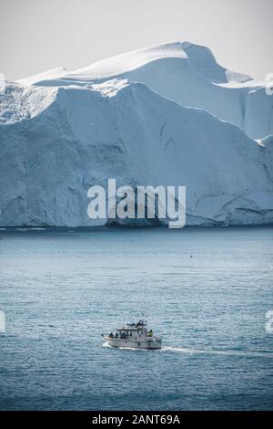 Passeggeri della nave di crociera in barca a vela attraverso le acque ghiacciate del paesaggio artico di Ilulissat. Una piccola barca tra gli iceberg. Crociera in barca a vela tra Foto Stock