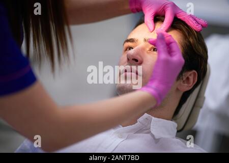 Guy casuale avente cosmetici antirughe, concetto di uomini cosmetici Foto Stock