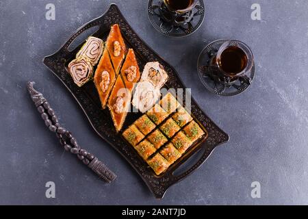 Assortimento di dolci orientali. Il Baklava e due tazze di tè su un calcestruzzo di colore blu nella tabella. Vista superiore, spazio di copia Foto Stock