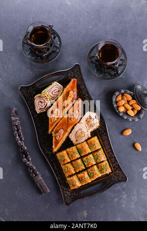 Assortimento di dolci orientali. Il Baklava e due tazze di tè su un calcestruzzo di colore blu nella tabella. Vista superiore, spazio di copia Foto Stock