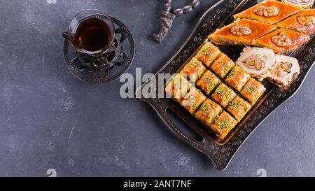 Assortimento di dolci orientali. Il Baklava e due tazze di tè su un calcestruzzo di colore blu nella tabella. Vista superiore, copia Spazio, immagine banner Foto Stock