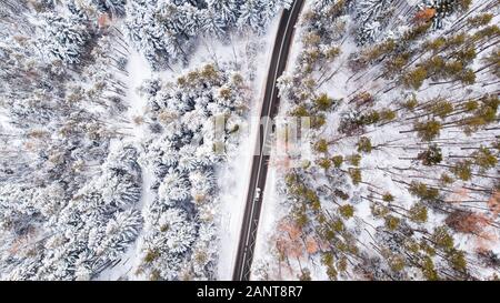 In auto attraverso boschi innevati in inverno Wonderland, Top Down Vista aerea. Foto Stock