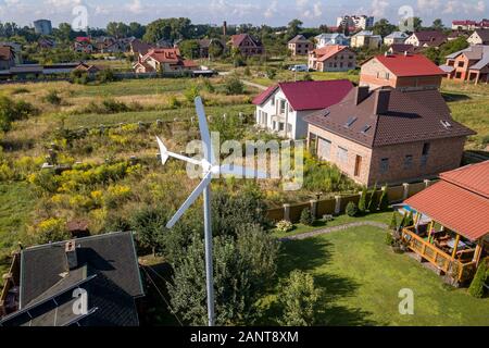 Vista aerea di una nuova casa autonoma con i pannelli solari, acqua radiatori di riscaldamento sul tetto e vento a turbina di potenza sul verde giardino. Foto Stock