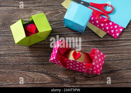 Box il giorno di San Valentino, Festa della Mamma o regali di compleanno. Regali di San Valentino con una carta rossa cuore su di un tavolo di legno. Foto Stock