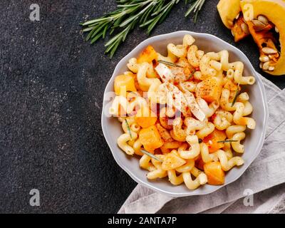 Fusilli con zucca, rosmarino e formaggio brie. Idea ricetta pasta. Cibo vegetariano. Pasta fatta in casa piatto in ciotola grigio nero su sfondo di calcestruzzo. Copia dello spazio. Vista superiore piatta o laici. Foto Stock