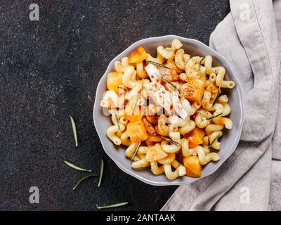 Fusilli con zucca, rosmarino e formaggio brie. Idea ricetta pasta. Cibo vegetariano. Pasta fatta in casa piatto in ciotola grigio nero su sfondo di calcestruzzo. Copia dello spazio. Vista superiore piatta o laici. Foto Stock