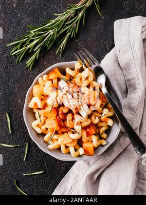 Fusilli con zucca, rosmarino e formaggio brie. Idea ricetta pasta. Cibo vegetariano. Pasta fatta in casa piatto in ciotola grigio nero su sfondo di calcestruzzo. Copia dello spazio. Vista superiore piatta o laici. Foto Stock