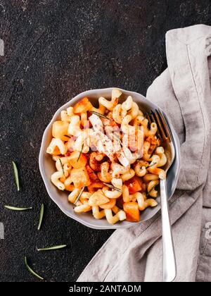 Fusilli con zucca, rosmarino e formaggio brie. Idea ricetta pasta. Cibo vegetariano. Pasta fatta in casa piatto in ciotola grigio nero su sfondo di calcestruzzo. Copia dello spazio. Vista superiore piatta o laici. Foto Stock