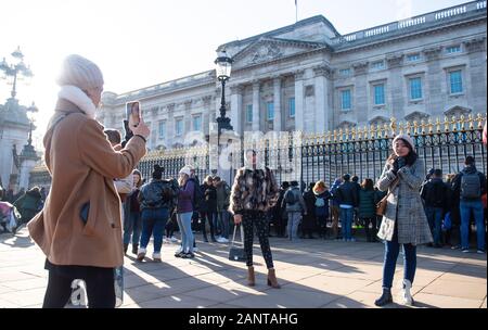 I turisti scattare foto al di fuori dei cancelli di Buckingham Palace, London, a seguito di una dichiarazione dalla Regina Elisabetta II e Buckingham Palace che il Duca e la Duchessa di Sussex hanno concluso le trattative più tornare indietro dalla loro royal ruoli. Foto Stock