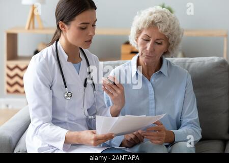 Medico azienda documenti, consultazione donna anziana circa checkup risultato Foto Stock