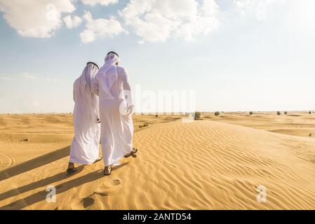 Arabian uomini witk kandora a piedi nel deserto - Ritratto di due medio orientale di adulti con il tradizionale abito arabo Foto Stock