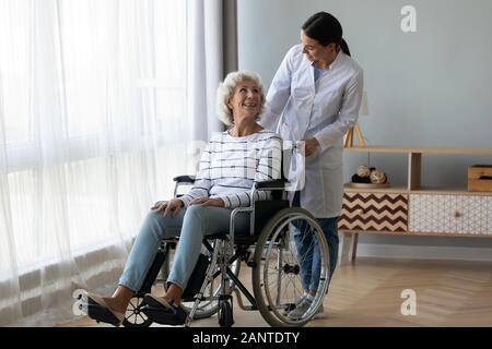 Il caregiver aiutare anziani disabili donna in carrozzella a casa Foto Stock