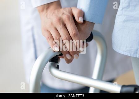 Close up caregiver mantenere vecchi donna mano su walker Foto Stock