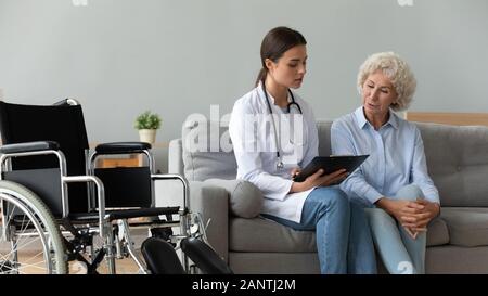 Grave consulenza medico paziente disabile circa checkup risultati a casa Foto Stock