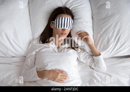 Vista superiore bella donna che indossa la maschera dormire sdraiati a letto Foto Stock