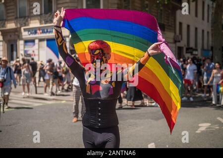 29 Giugno 2019, Parigi, Francia. Giornata Parata Gay Pride. Giovane uomo che tiene una bandiera che guarda la macchina fotografica . Il suo viso e il suo corpo sono dipinti ! Design bellissimo Foto Stock