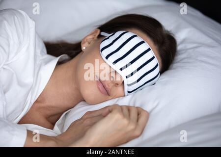 Close up bella donna che indossa la maschera dormire sdraiati a letto Foto Stock